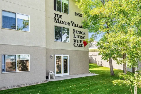 Side of the residence with windows, a door, building lettering and trees