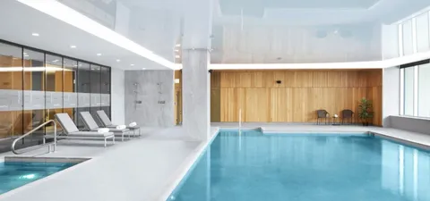 Indoor swimming pool with lounge chairs and metal handrails