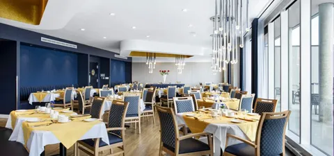 Dining room with set tables, yellow tablecloths and tall windows