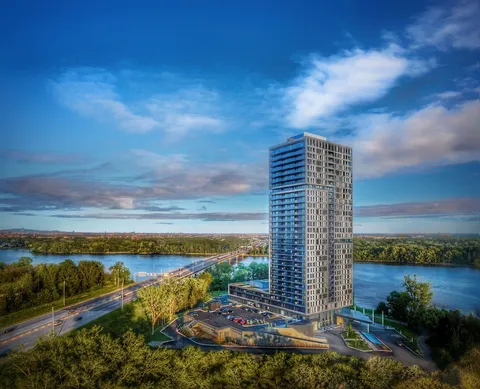 Tall residential tower beside a river and bridge