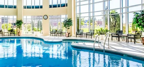 Indoor pool with handrails beside floor-to-ceiling windows