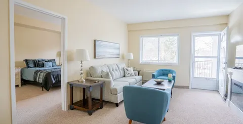 Furnished suite with sitting area, bedroom doorway and a patio door.