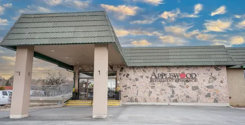 Covered driveway entrance with stone walls and the residence name.