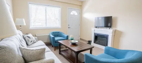 Sitting area with a sofa, armchairs, television and exterior door.