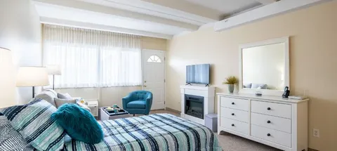 Studio suite with a bed, dresser and sitting area.