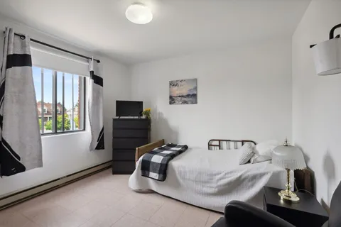 Bedroom with a bed, armchair and wooden furniture beside a window