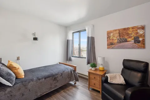 Bedroom with a bed, armchair, bedside cabinet and a landscape picture
