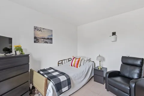 Bedroom with a bed, chest of drawers, armchair and landscape picture