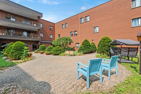 Paved courtyard with chairs, small trees and landscaped beds