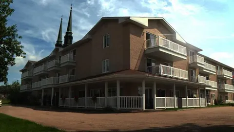 Brick building with white balconies, a covered porch and a front lawn