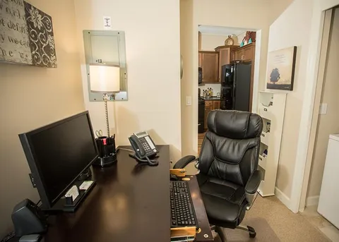 Suite desk with a monitor, office chair and shelving.