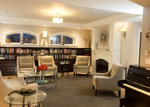 Library lounge with armchairs, bookshelves and a piano.