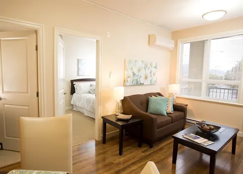 Suite living area with a sofa and coffee table beside a bedroom.