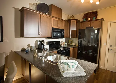 Suite kitchenette with wooden cabinets and black appliances.