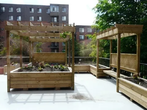 Wooden pergola above raised garden beds and a bench