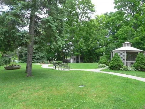 Lawn with garden chairs, a white trellis and a gazebo
