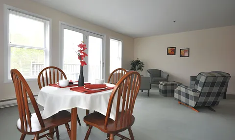 Suite living and dining area with table, chairs and large windows.