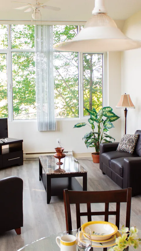 Suite sitting area with a sofa, dining table and large windows.