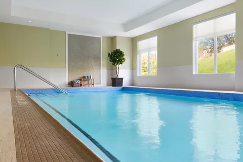 Indoor swimming pool beside large windows.