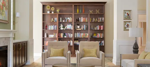 Lounge armchairs beside a fireplace and built-in bookshelves.