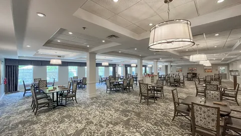Dining room with rows of tables, upholstered chairs and hanging lights