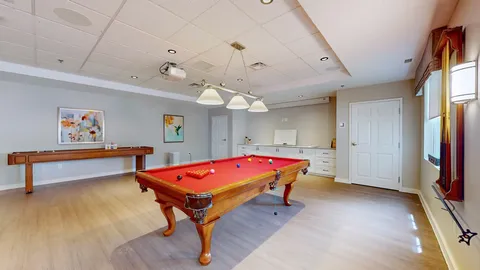 Games room with a red pool table, shuffleboard table and kitchenette