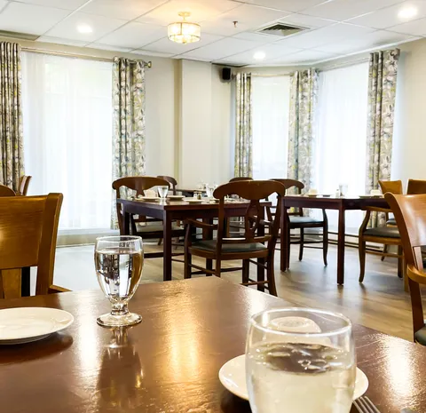Dining room with wooden tables and chairs beside tall windows