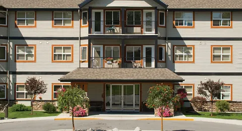 Residence front with balconies, a covered entrance and planted flower beds