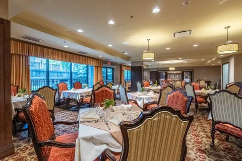 Dining room with patterned chairs, white tablecloths and windows