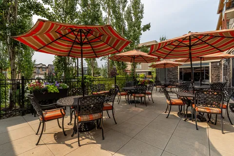 Patio with metal tables, chairs, striped umbrellas and flower planters