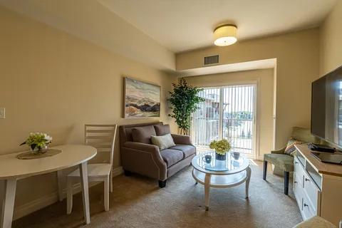 Sitting area with a grey sofa, round dining table and glass balcony door