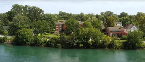 Residence viewed across the creek, surrounded by mature trees.