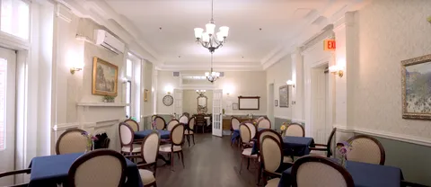 Dining room with oval-backed chairs and tables with blue cloths.