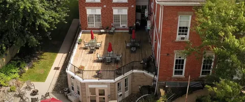 Raised patio with tables and chairs beside the brick residence.