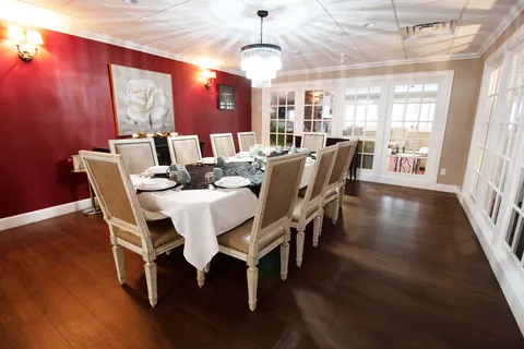 Long dining table beneath a chandelier in a red-walled room