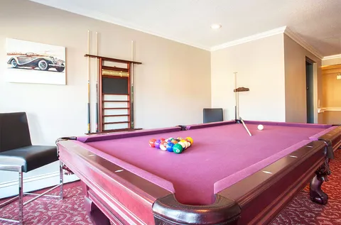 Billiard table with purple cloth and a rack of cues