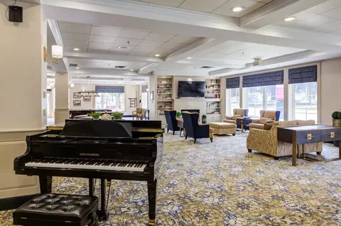 Room with a grand piano, armchairs and tables beside windows