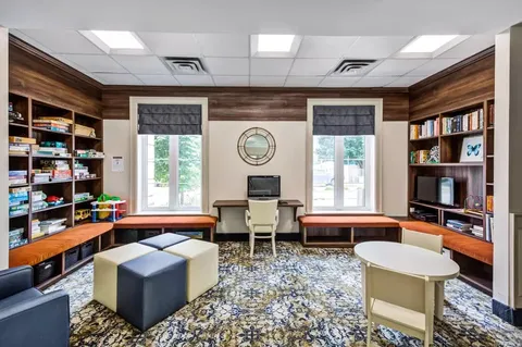 Room with bookshelves, game boxes, tables and a computer