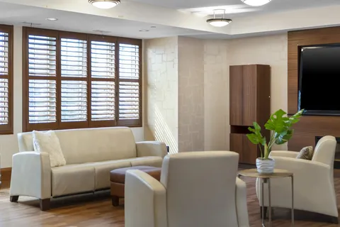 Sofa and armchairs around a table beside windows with wooden blinds