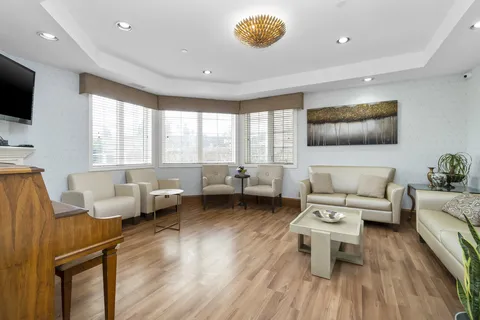 Armchairs, a sofa and a piano in a bright room with several windows