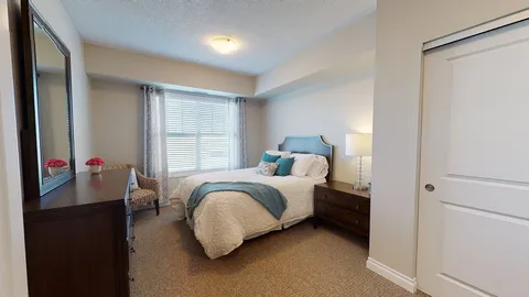 Bedroom with a bed, mirrored wardrobe and curtained window.