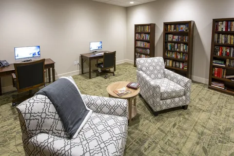 Library lounge with armchairs, bookshelves and computer desks.