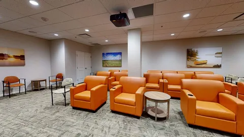 Screening room with rows of orange chairs and a projection screen.
