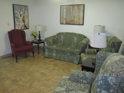 Sitting area with patterned chairs, a red armchair and framed wall pictures