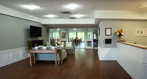 Reception counter beside a green sofa, glass doors and lamps