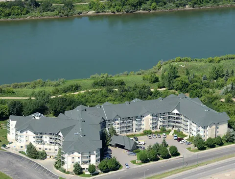 Aerial view of the residence beside the river and a tree-lined park.