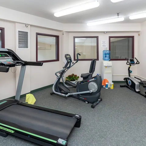 Fitness room with a treadmill, exercise bicycle and other equipment.