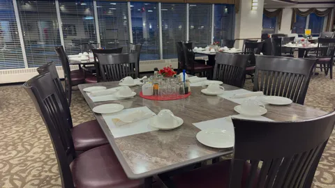 Dining room tables set with plates beside large windows.
