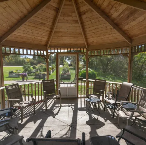 Covered gazebo with tables and chairs overlooking the garden.