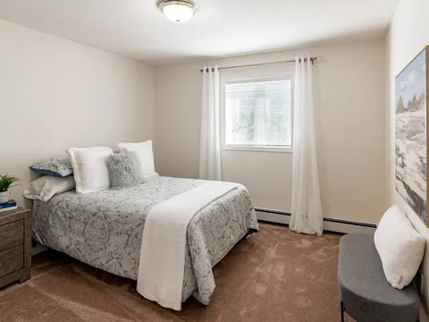 Bedroom with a bed, chair and curtained window.